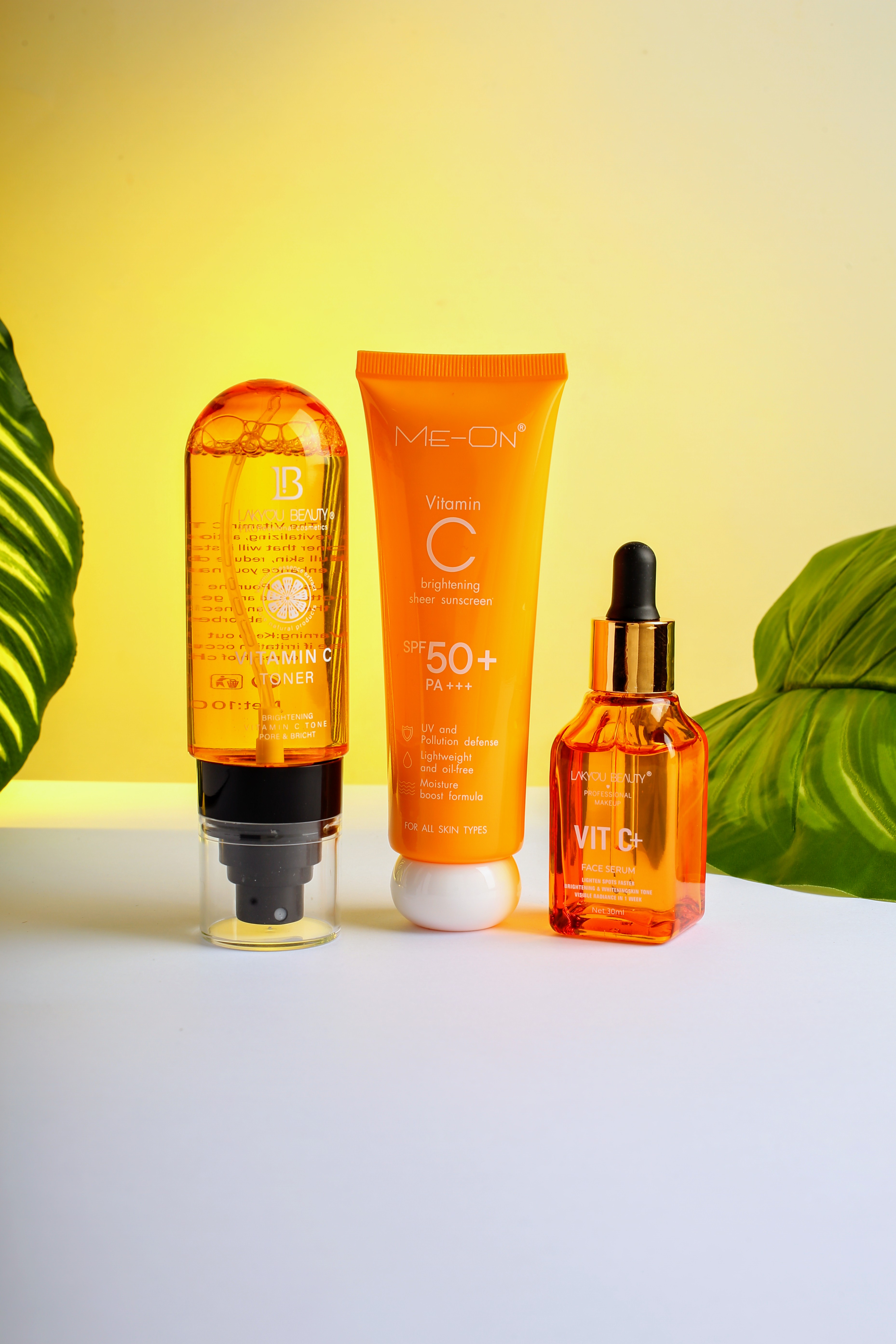 Skincare products including sunscreen and serum with yellow background and leaves